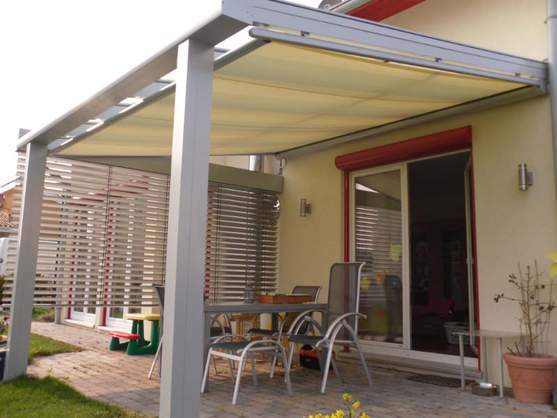 Moderne Terrassenüberdachung aus Aluminium mit Markise und Sitzgruppe im Garten.